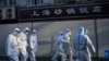身穿防护服的防疫人员在上海一处因发现新冠疫情而被封闭的小区的屏障外。（2022年3月15日）