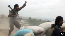FILE - An Afghan National Army soldier, left, shouts against the Taliban, after firing a rocket towards Taliban positions, on the outskirts of Kunduz, northern Afghanistan, April 16, 2016.
